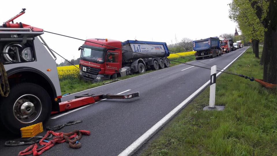 Heavy-duty recovery after truck accident: towing service secures and pulls a stranded semi-truck back onto the road using a winch.